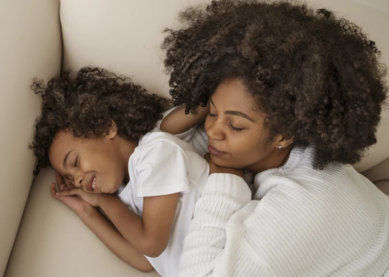 Mom cuddling with daughter on the couch.